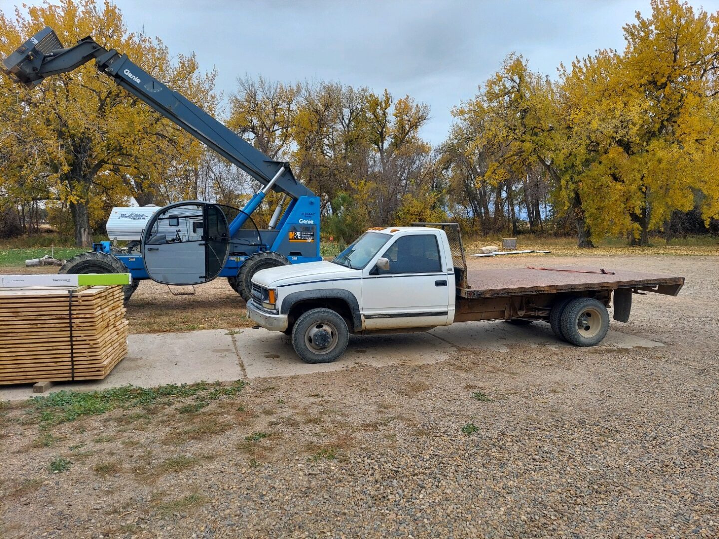 A truck is parked in the dirt near a tree.