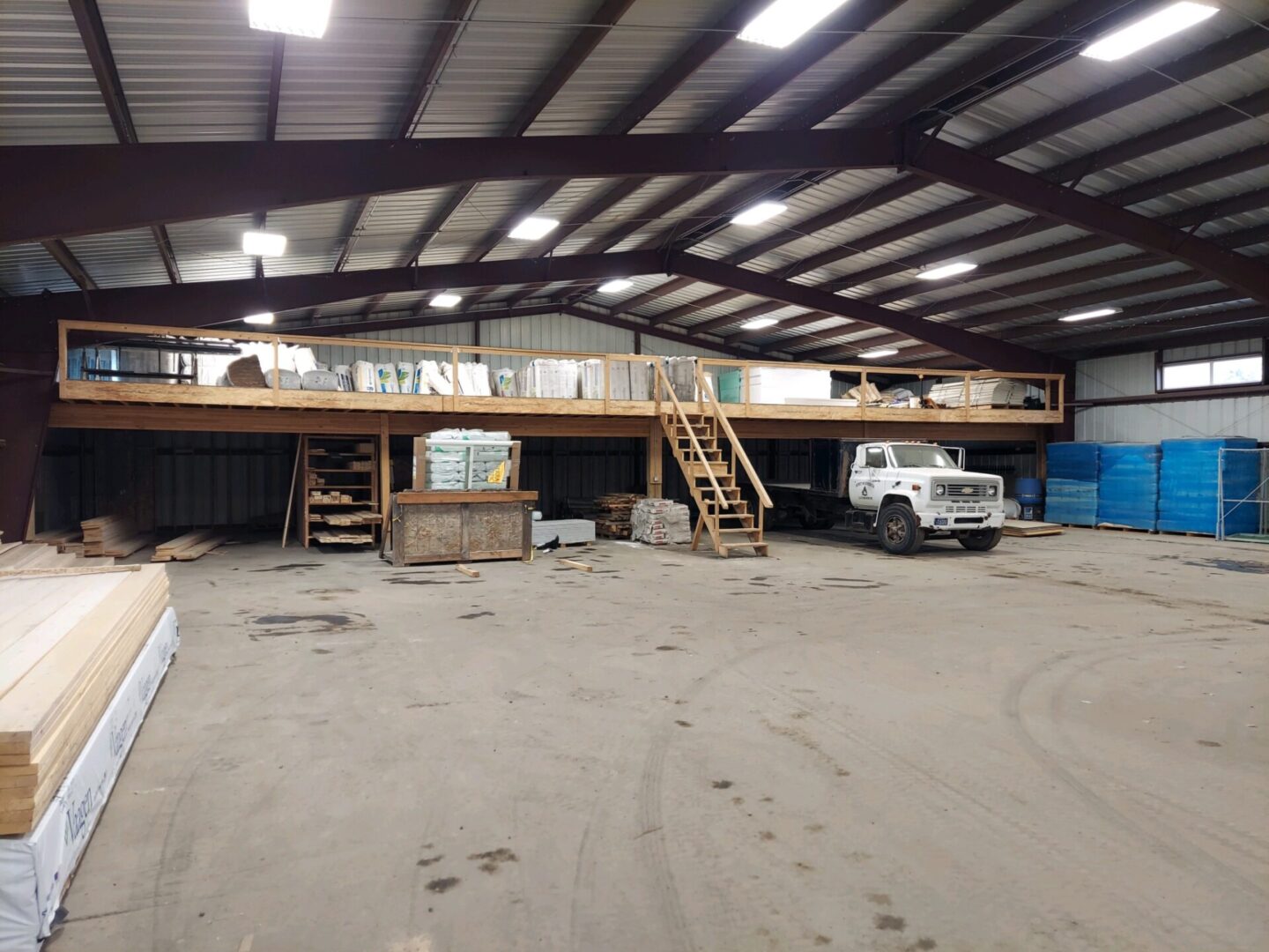 A large warehouse with stairs and a truck parked in it.